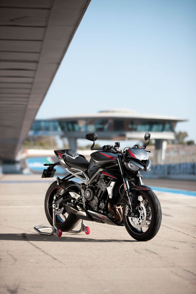 A gray-and-red 2020 Triumph Street Triple RS on a rear-wheel stand at a racetrack