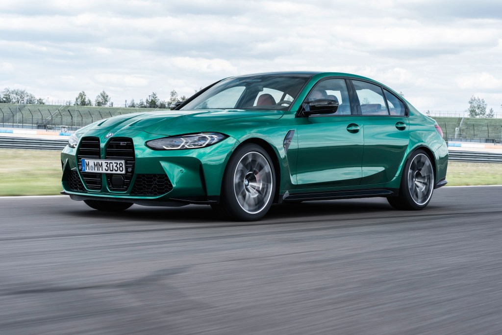 A green 2021 BMW M3 driving on a racetrack