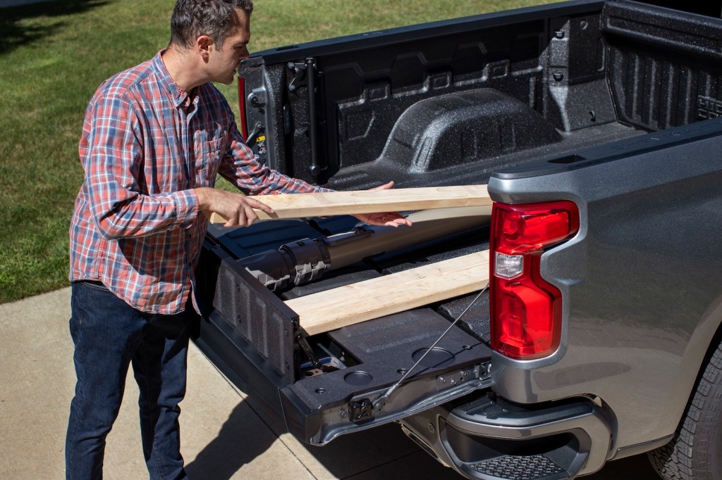 A man loading wood into the 2021 Chevy Silverado's Multi-Flex Tailgate