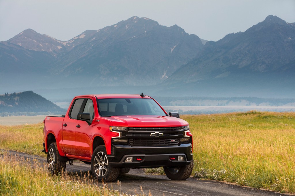 2021 Chevy Silverado Trail Boss in red parked in front of some mountains