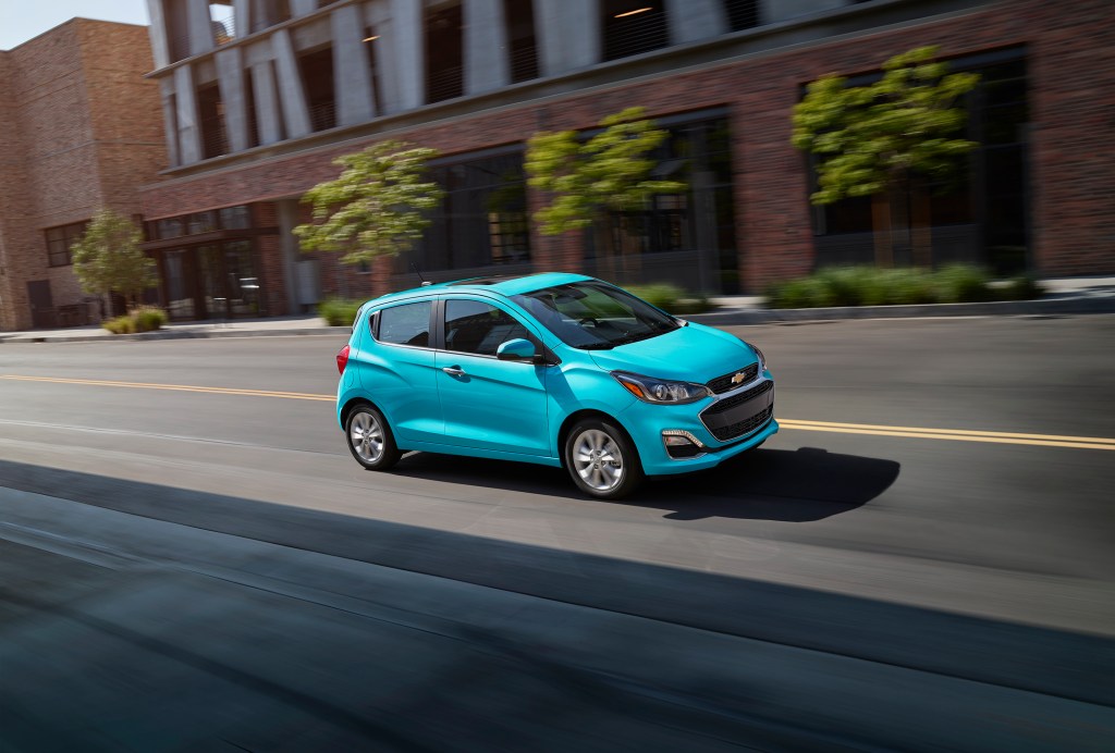a blue Chevy Spark driving on a city street