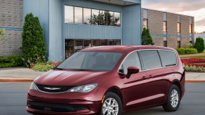 A dark-red 2021 Chrysler Voyager parked outside a modern two-story building