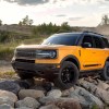 An orange metallic 2021 Ford Bronco Sport compact crossover SUV parked on rocks beside a dirt road