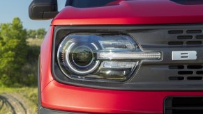 The right front headlight and black grille of a red 2021 Ford Bronco Sport SUV