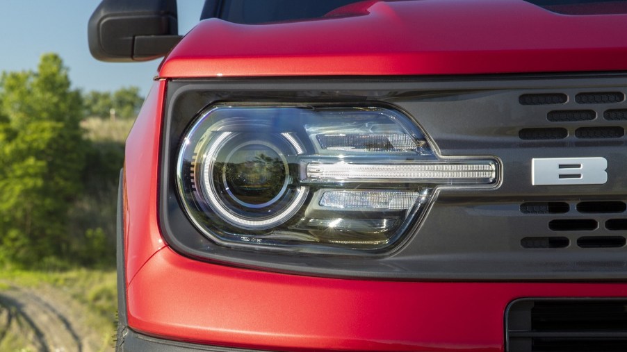 The right front headlight and black grille of a red 2021 Ford Bronco Sport SUV