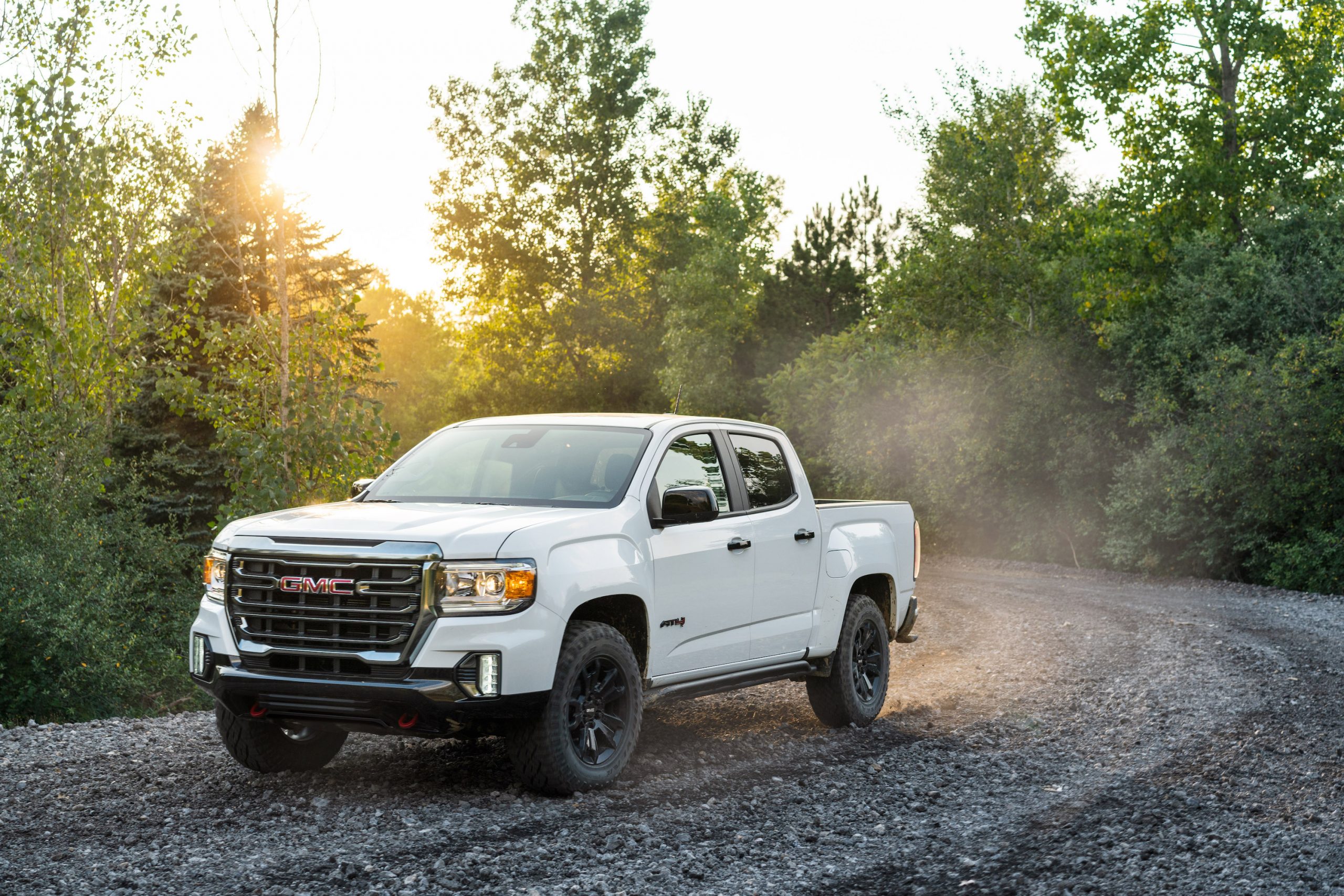 a white 2021 GMC Canyon drives off-road on a gravel trail.  