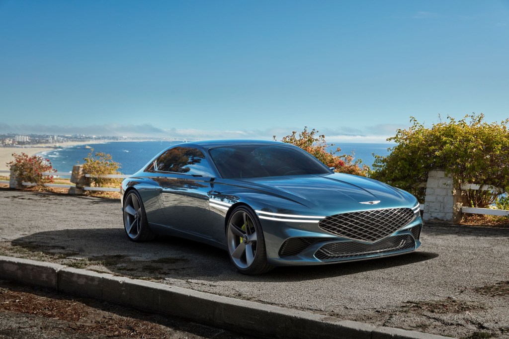The green 2021 Genesis X Concept parked overlooking a sandy beach