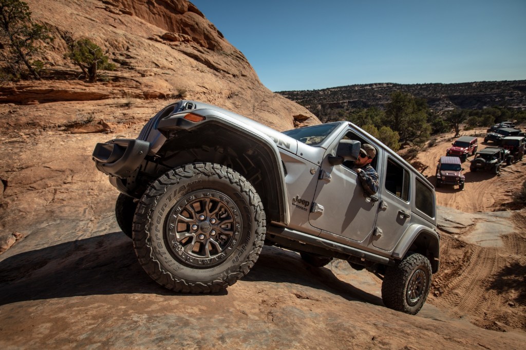 A silver 2021 Jeep Wrangler Rubicon 392 SUV navigates a red-rock mountain on a clear day