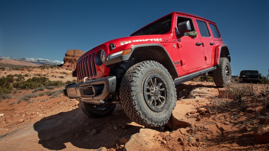 A red 2021 Jeep Wrangler Rubicon 392 SUV parked on rocks on the side of a hill
