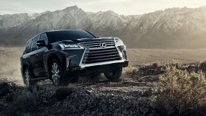 A black 2021 Lexus LX 570 climbs up a hill in the desert by some mountains