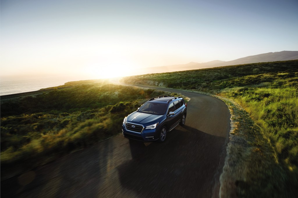 A blue 2021 Subaru Ascent SUV driving down a country road