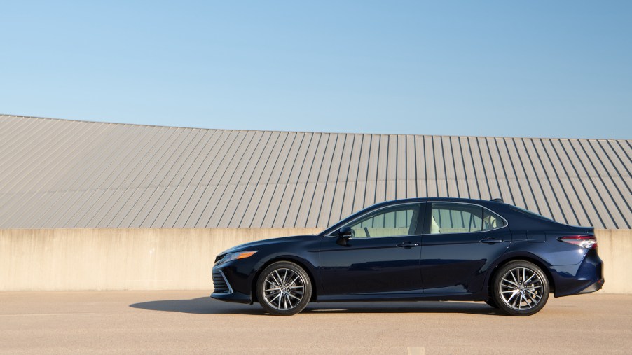 A navy-blue 2021 Toyota Camry XLE midsize sedan parked on a beige concrete roof with a blue sky in the background