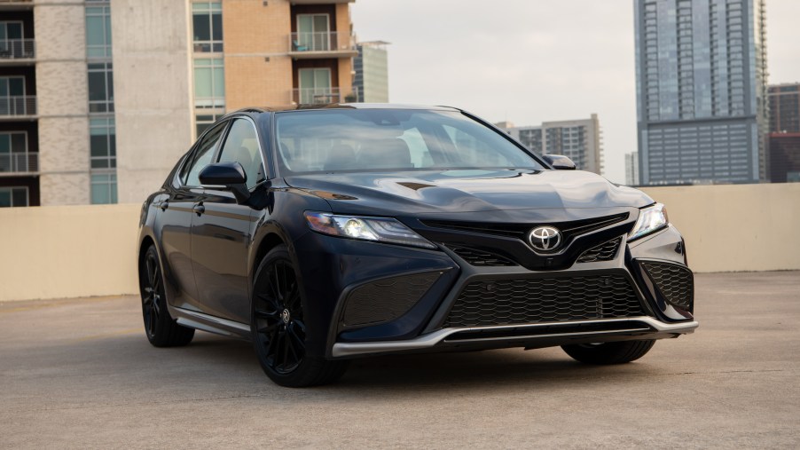 A dark-colored 2021 Toyota Camry XSE Blueprint midsize sedan parked on the roof of a building in a city