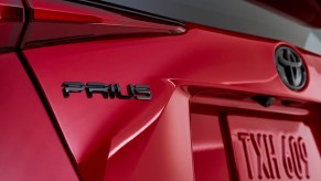 A closeup of the left rear area of a red 2021 Toyota Prius hybrid car