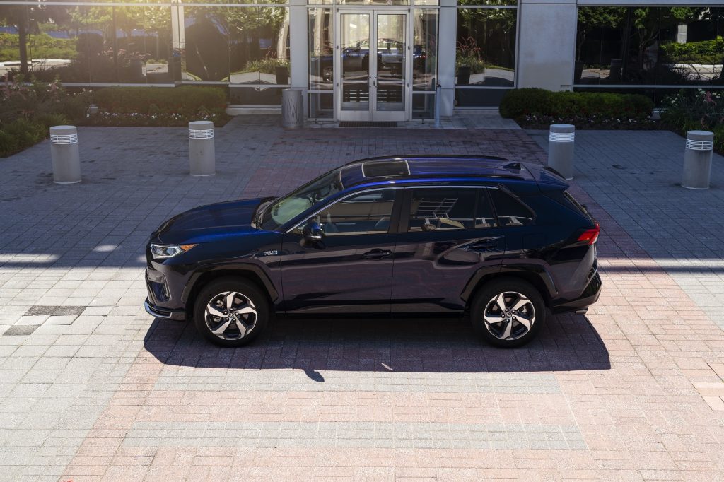 A dark-blue metallic 2021 Toyota RAV4 Prime plug-in hybrid compact SUV parked outside a glass building