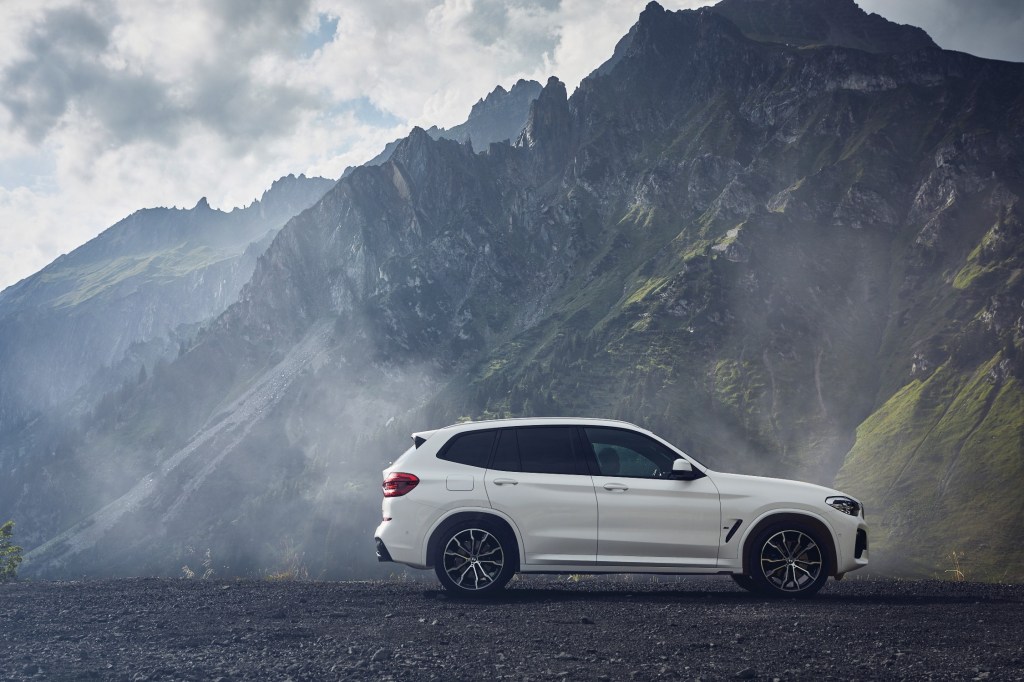 The side profile of a white bmw x3 with mountains in the distance