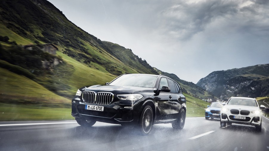 Three BMWs driving down a wet mountain road