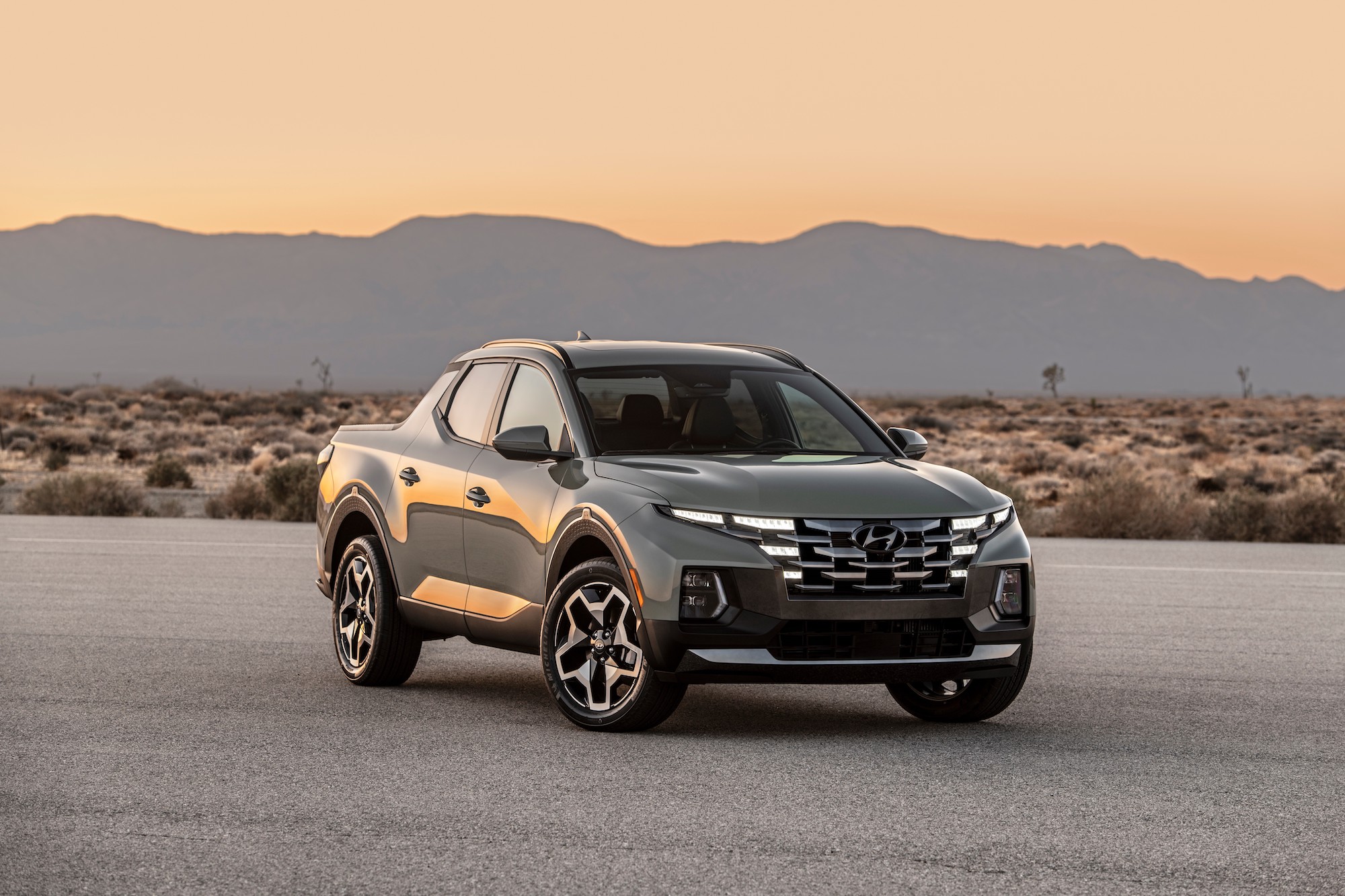 A gray 2022 Hyundai Santa Cruz parked on the pavement in a desert with mountains