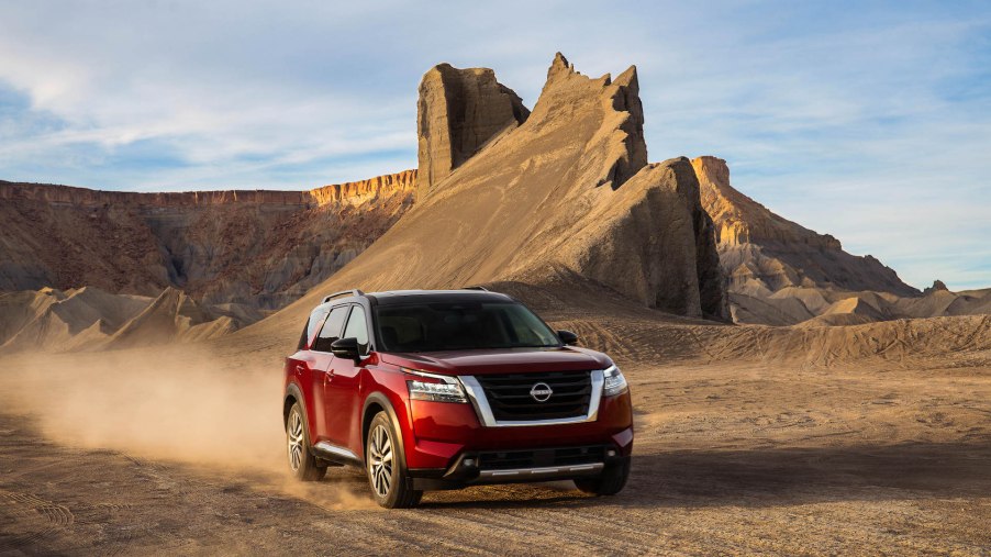 An image of a 2022 Nissan Pathfinder parked outdoors, in the sand..