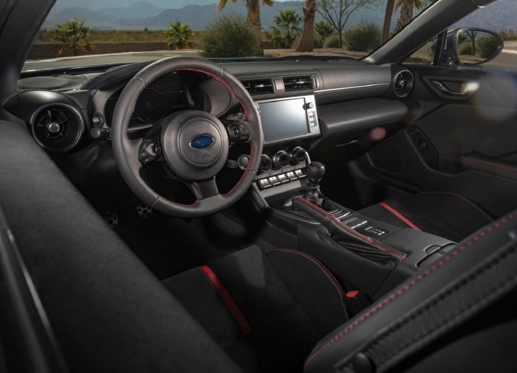 The red-and-black front seats and dashboard of a 2022 Subaru BRZ seen from the drivers-side window