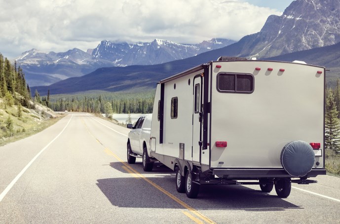 a truck towing a trailer RV camper toward the mountains