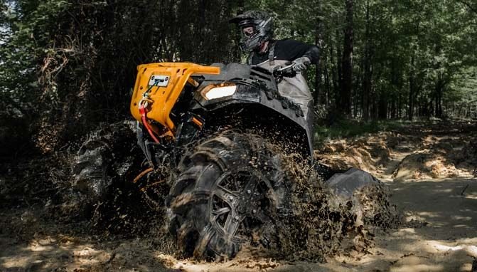 An ATV powering through deep mud with new tires