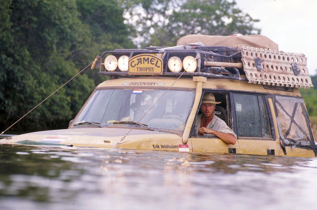 A yellow Land Rover Discovery submerged in a river during the Camel Trophy