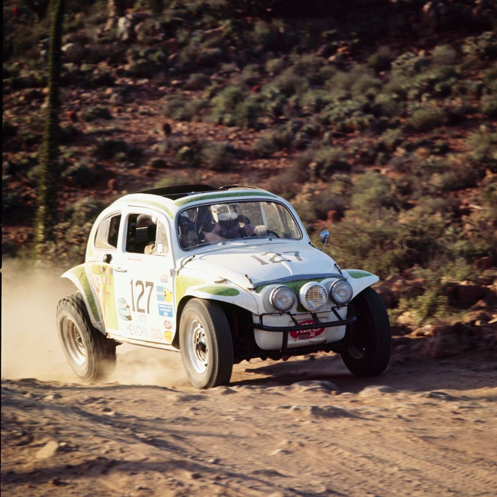 A white-and-green classic Volkswagen Beetle racing in the Baja Peninsula desert in the 1972 NORRA Mexican 1000