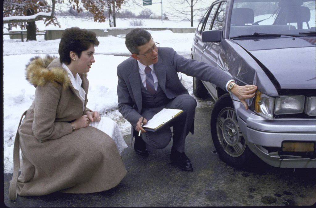 Insurance adjuster looking at car damage