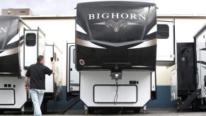 A salesperson holds a mobile device while using video chat to show a potential customer a Heartland Recreational Vehicles LLC Big Horn travel trailer at Motor Sportsland RV dealership