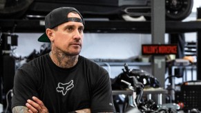 Carey Hart in his workshop garage with a hot rod on a lift