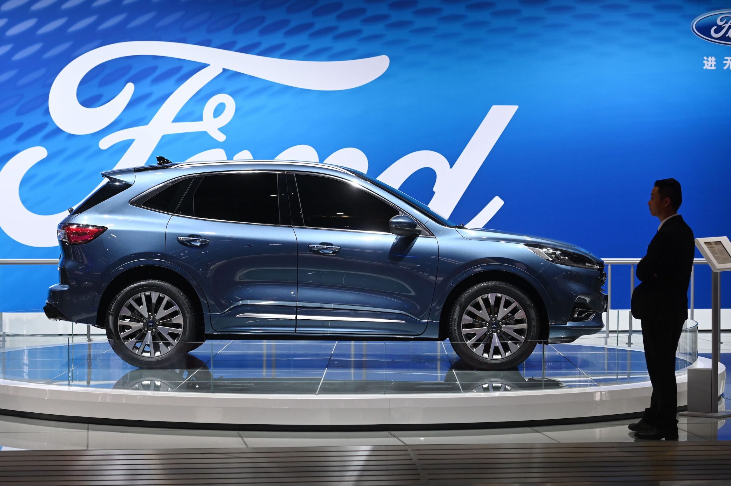 A staff member stands beside a Ford Escape Titanium at the Shanghai Auto Show