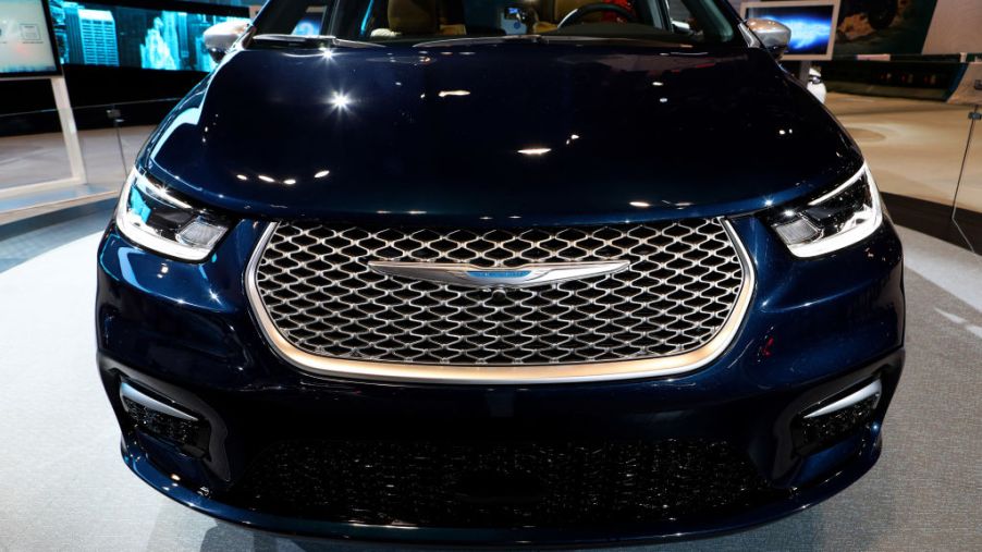 the grille of a dark blue 2021 Chrysler Pacifica minivan on display at an auto show
