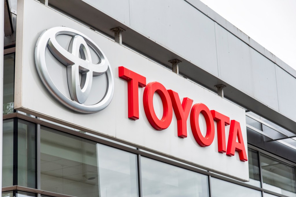a silver Toyota logo with the red TOYOTA letters on the side of a dealership building