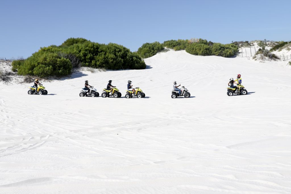 several ATV riders traversing scenic sand dunes