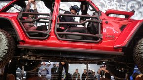 An attendee wears a virtual reality headset while riding in a show version of a red 2020 Jeep Wrangler Unlimited 4xe plug-in hybrid electric vehicle at CES 2020