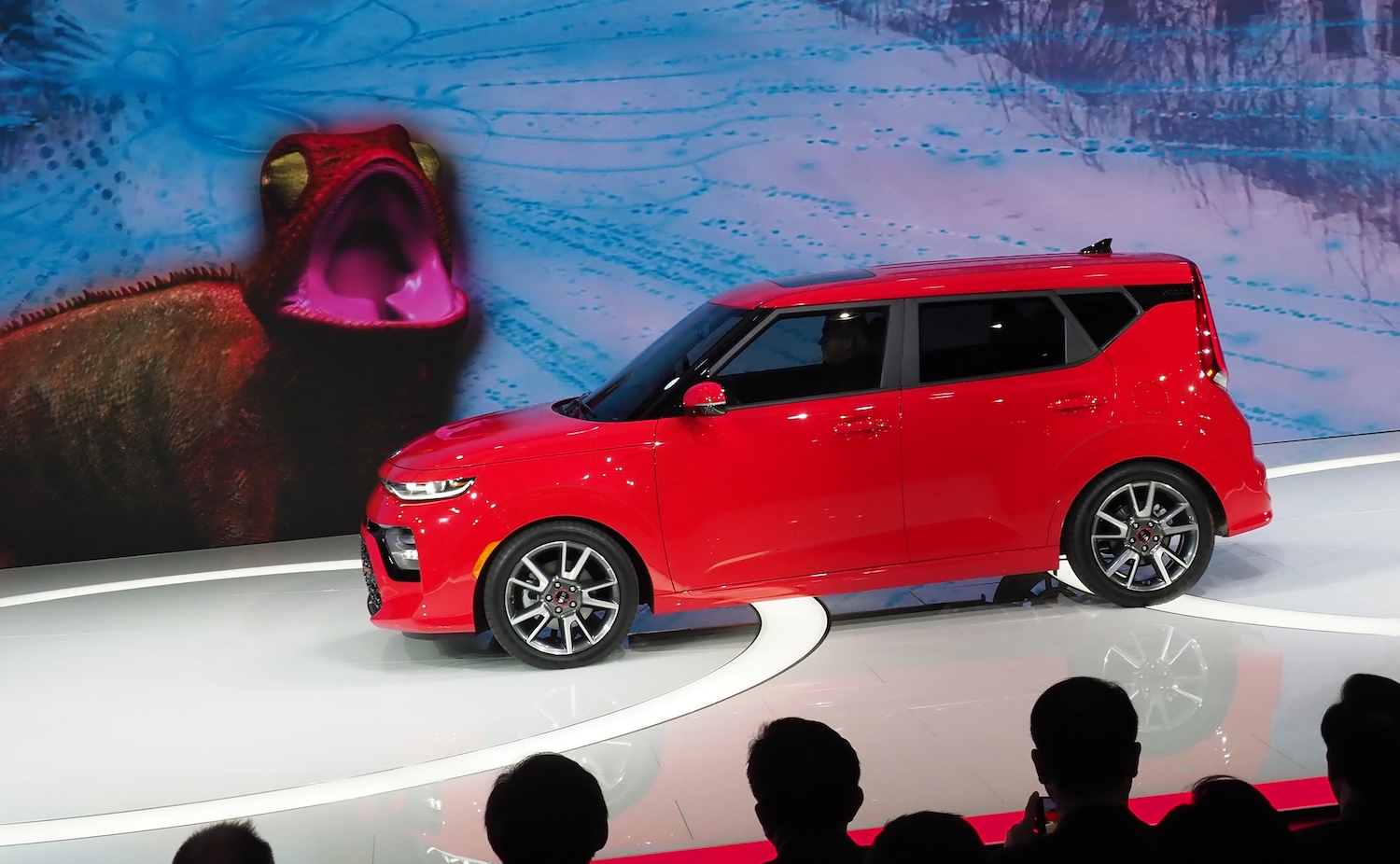 A red Kia Soul GT being unveiled at an auto show.