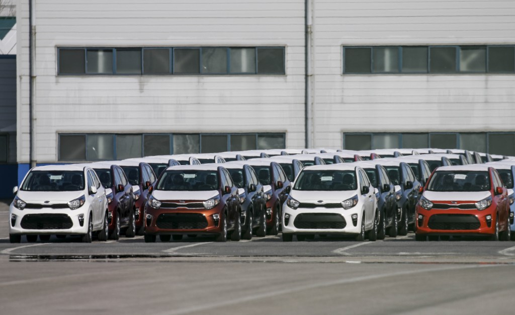 Kia cars sit in a row on awaiting export