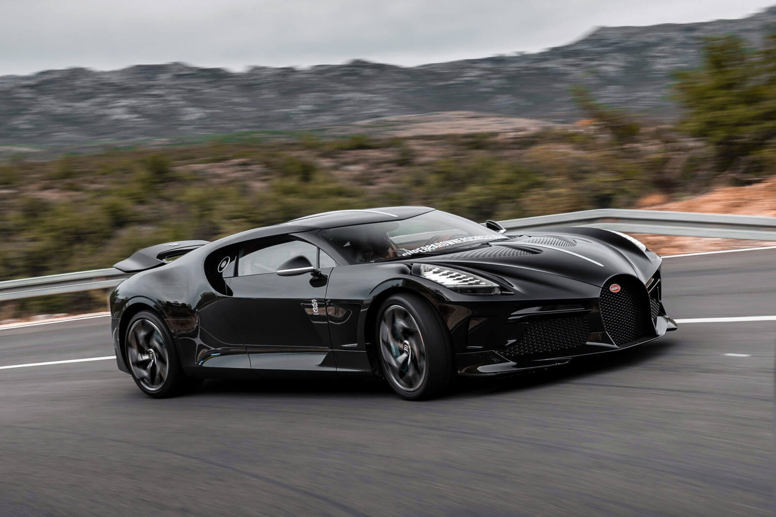 Front view of a black La Voiture Noire Bugatti on a curving road