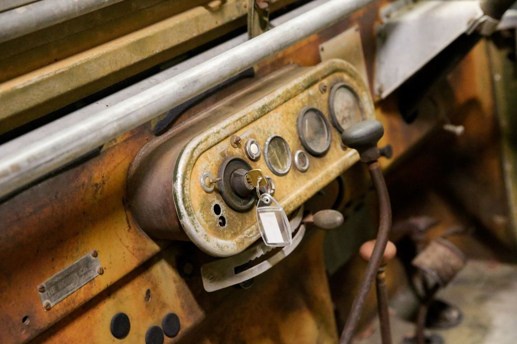 A closeup of a Land Rover Series One's ignition switch and starter button with its key