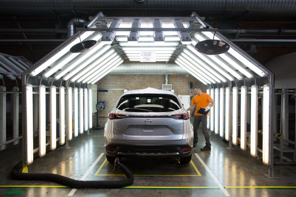A worker inspects a Mazda Motor Corp. CX-9 sports utility vehicle (SUV) in a light tunnel at the Mazda Sollers Manufacturing Rus LLC plant
