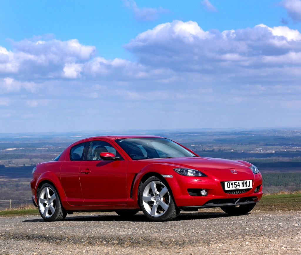 Red Mazda RX8 coupe JDM car parked on a hill