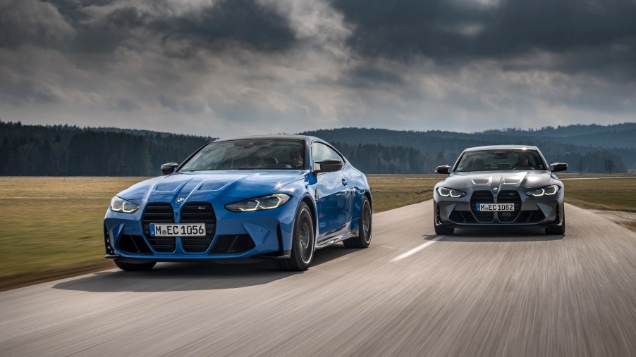An image of a BMW M3 and M4 xDrive driving on a road.