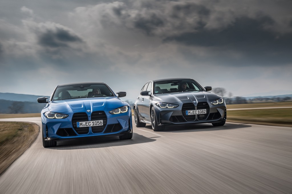 An image of a BMW M3 and M4 xDrive driving on a road.