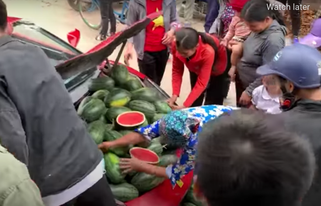 Phony Ferrari with crowd around open frunk full of melons