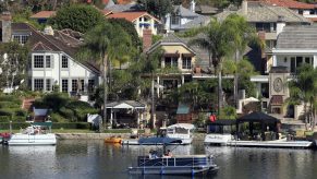 An electric-powered pontoon boat skims across Lake Mission Viejo, past the homes and private docks