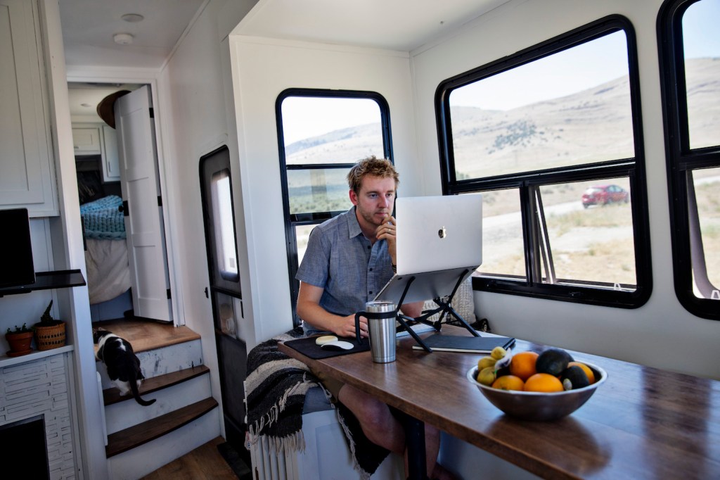 A man sitting inside of his RV, accessing RV WiFi via his computer.