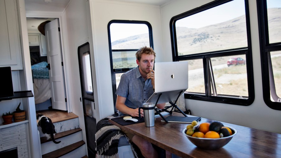 A man sitting inside of his RV, accessing RV WiFi via his computer.