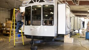 Workers assemble the exterior finish of a destination recreational vehicle (RV) at the HL Enterprise manufacturing facility in Elkhart, Indiana, U.S.