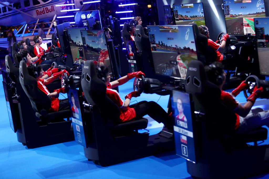 Red-clad racers competing on simulators in the 2019 FIA Gran Turismo World Tour Nations Cup in Salzburg